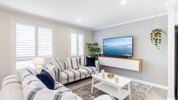 Un salon moderne avec un canapé à rayures, une table basse et un téléviseur fixé au mur.