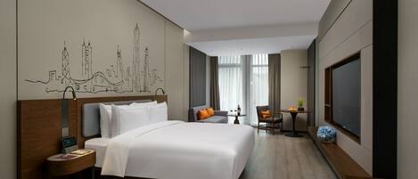 A hotel room with a large bed, a desk, a chair, a TV, and a cityscape mural on the wall.
