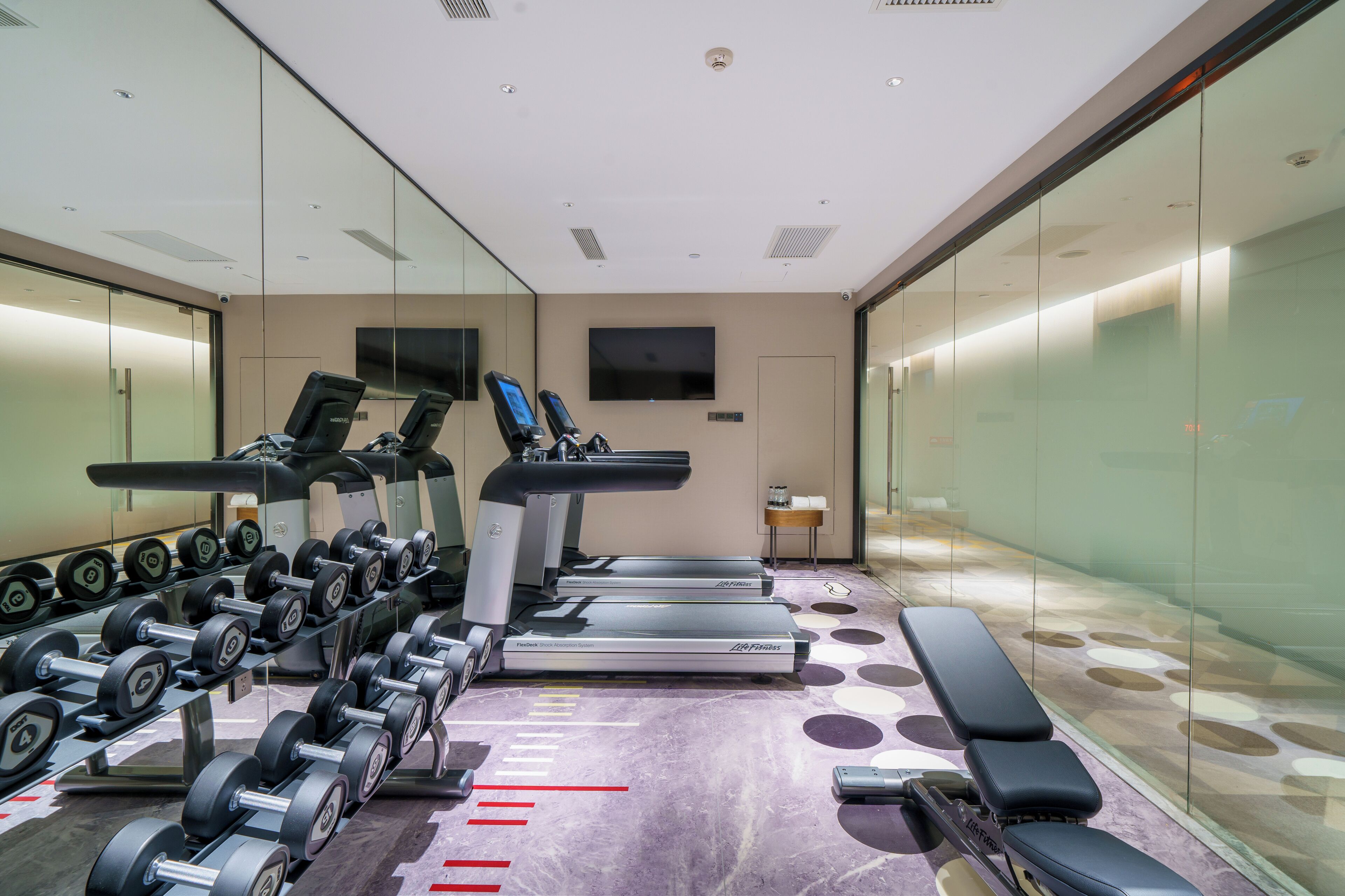 Une salle de sport moderne équipée de tapis de course, d’haltères et de bancs d’entraînement.