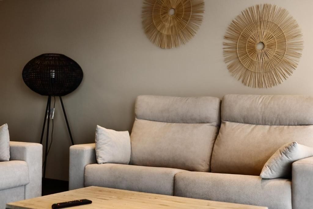 A living room with a beige sofa, two side tables, and a round floor lamp.