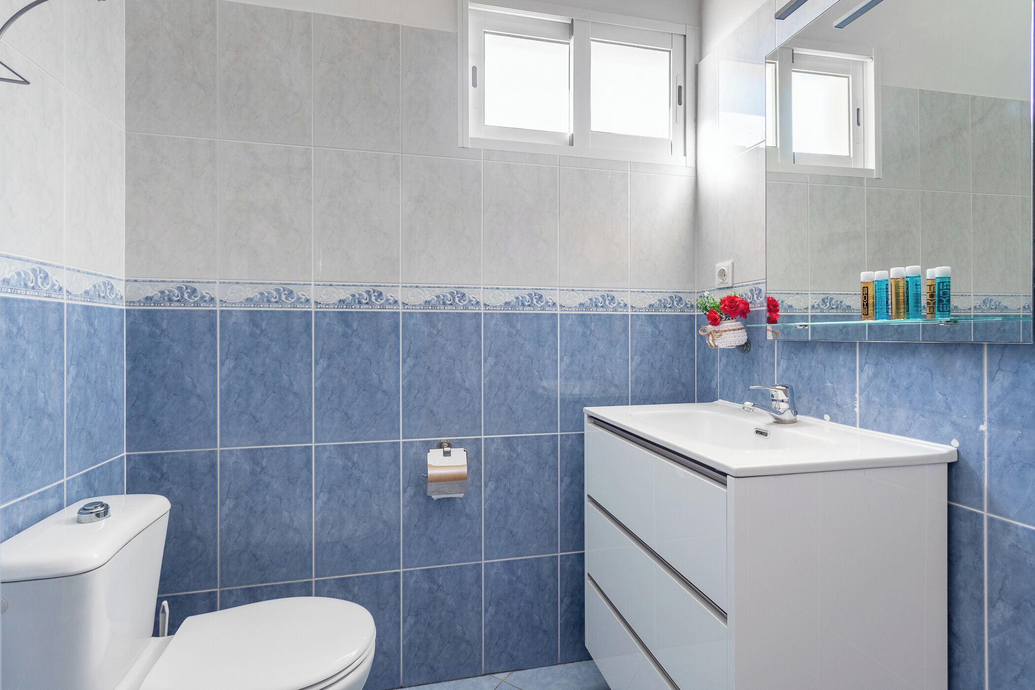 A bathroom with blue tiles, a white sink, and a toilet.