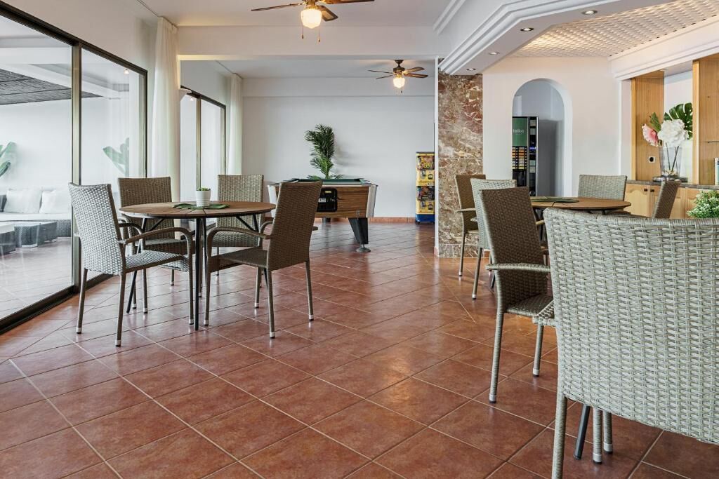 Un espace intérieur spacieux comprenant une table et des chaises, un ventilateur de plafond et une grande fenêtre.
