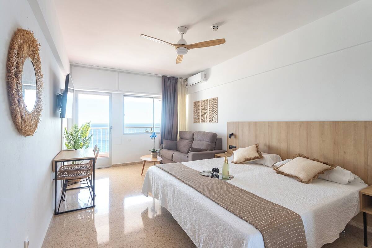 Ein modernes Hotelzimmer mit einem großen Bett, einem Schreibtisch und einem Balkon.
