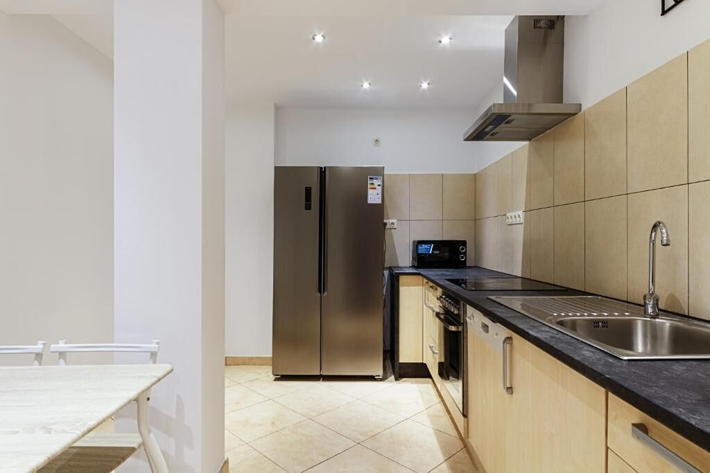 Una cocina moderna con electrodomésticos de acero inoxidable, encimera negra y muebles beige.