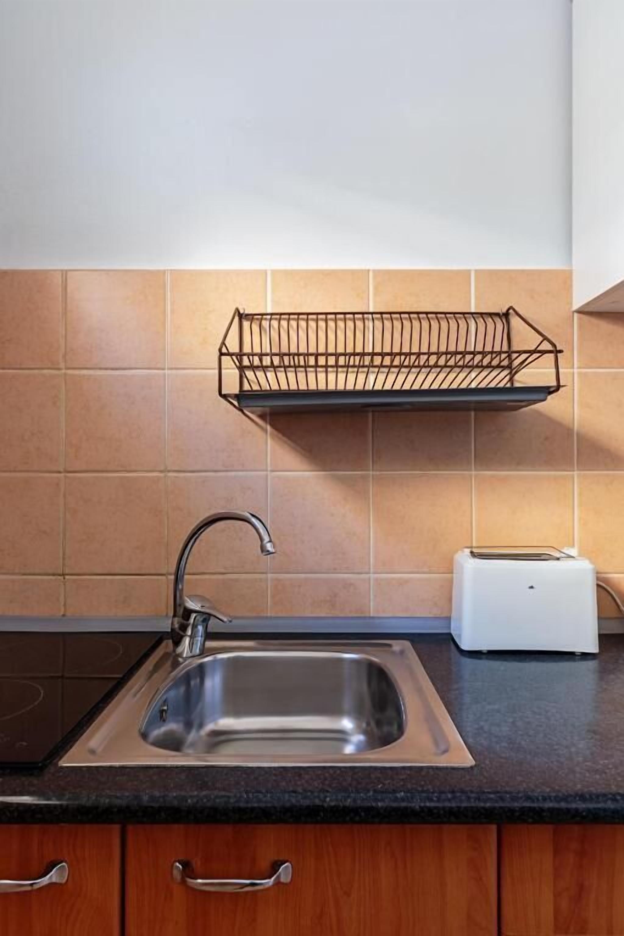 Eine Küche mit Spüle aus Edelstahl, einem Toaster und einem Drahtkorb-Regal.