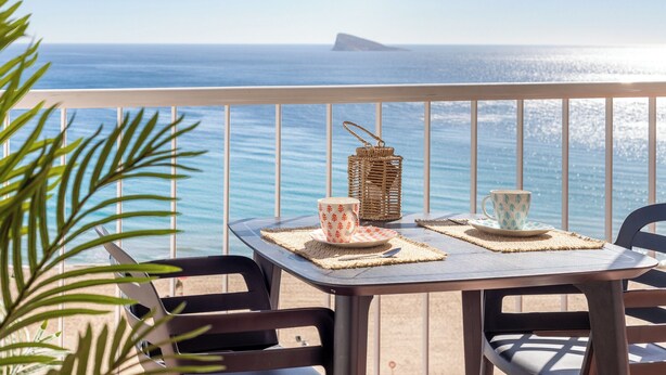 A balcony with a table set for two, overlooking the sea. - Apartamentos Mirador  (Benidorm)
