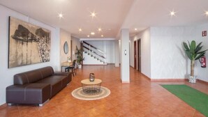 A spacious lobby with a brown leather sofa, a round coffee table, and a staircase in the background. - Apartamentos Mirador  (Benidorm)