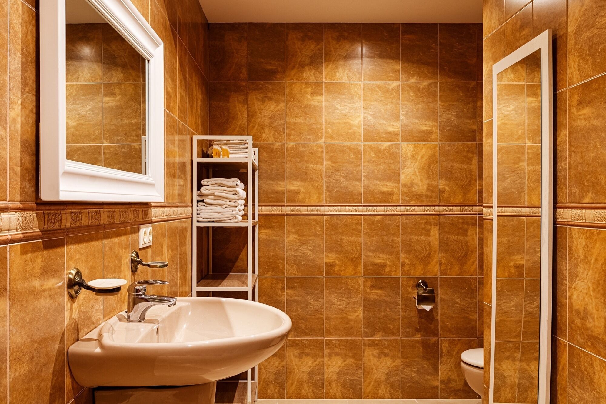 A bathroom with a sink, mirror, towel rack, and toilet.