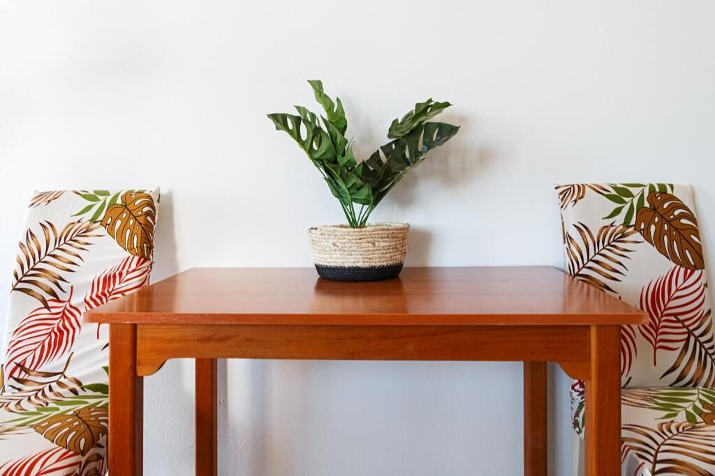 Una mesa de madera con una cesta tejida que contiene una planta verde.