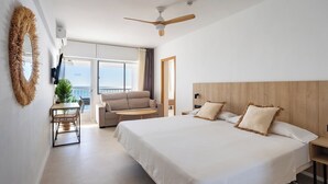 A hotel room with a bed, a ceiling fan, a TV, a balcony with a view, and a dining area with a table and chairs. - Apartamentos Mirador  (Benidorm)