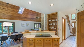 Une cuisine moderne avec des meubles en bois, un îlot central et un coin repas comprenant une table et des chaises.