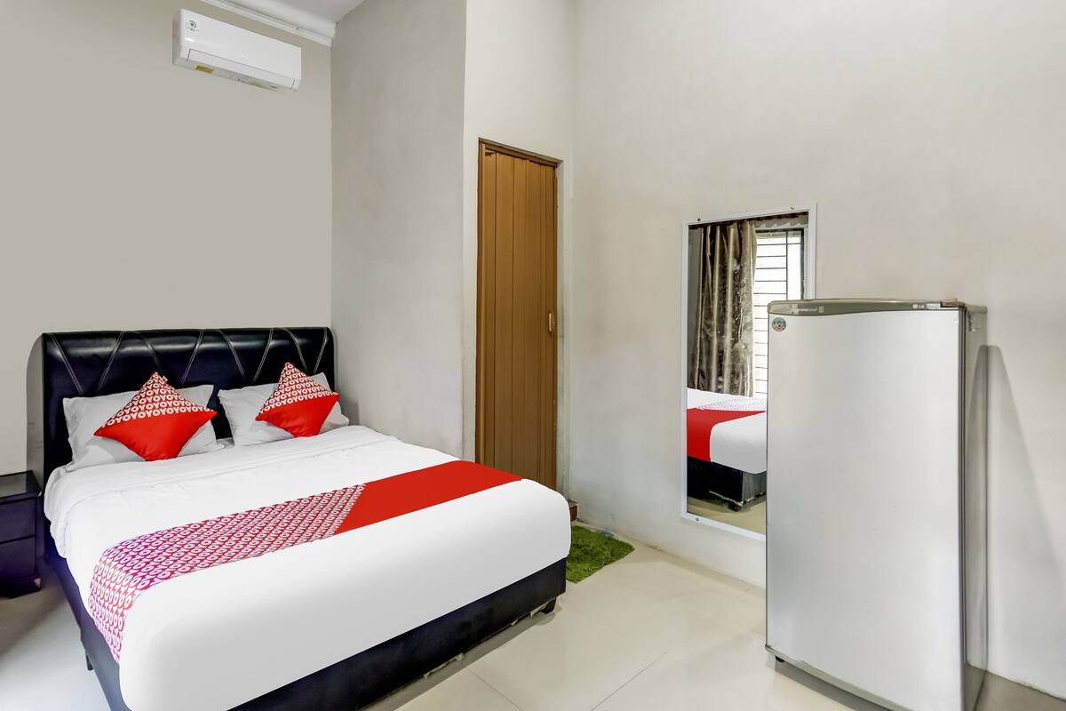 Ein Hotelzimmer mit Bett, Schrank, Kühlschrank und einem Fenster mit Vorhängen.