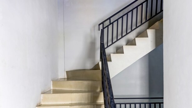 Un escalier avec des marches de couleur beige et une rampe en métal noir.