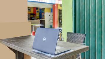 A laptop on a table with a chair, a green wall, and a colorful interior in the background.