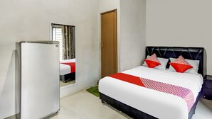 Une chambre d’hôtel avec un lit, une armoire, un miroir et une fenêtre.