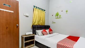 A bedroom with a bed, a nightstand, a wooden shelf, a door, and a wall with a window and wall stickers.