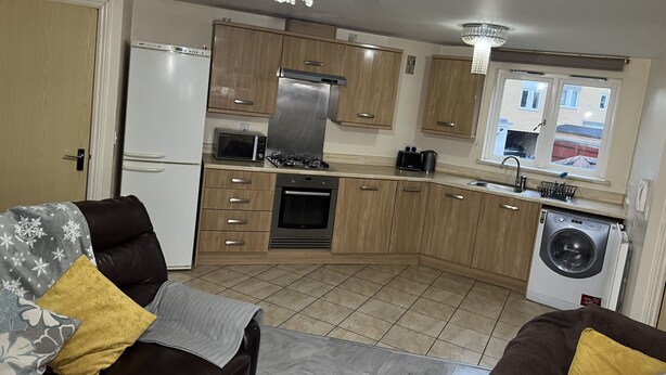 A compact kitchen with a refrigerator, microwave, stove, oven, and washing machine. - Flat In Willen - Milton Keynes suitable for contractors and family staycations  (Milton Keynes)