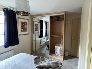 Cozy retreat with a large wardrobe, comfortable bed, and hanging light fixture.