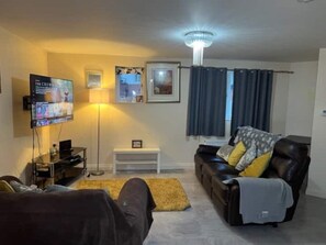 Relax in this cozy space with a flat-screen TV, comfortable sofa, and a side table.