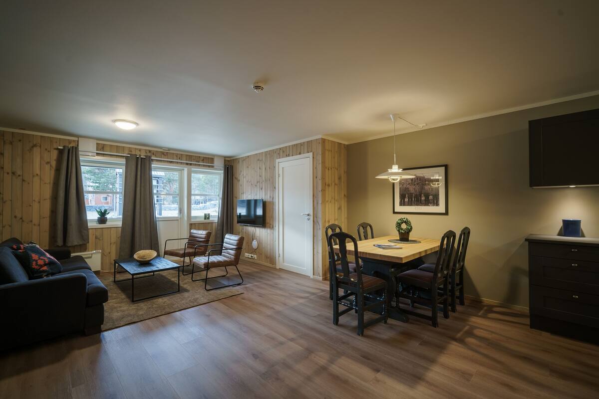 A modern living room with a sofa, coffee table, and dining area with chairs and a table.