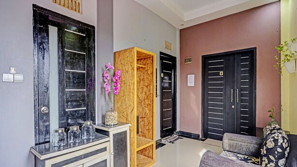 A modern living room with a grey sofa, a wooden cabinet, and a black door with a number plate. - Hotel O Lia Stay Syariah (Batam)