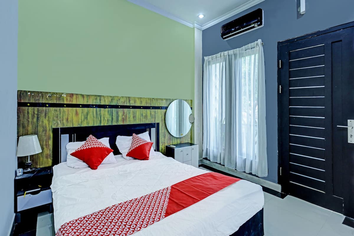 A hotel room with a bed, a nightstand, a mirror, a window with curtains, and a door.