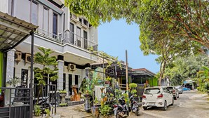 A residential street with parked cars and motorcycles, a gated entrance, and various potted plants. - Hotel O Lia Stay Syariah (Batam)