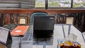 A room with a view of a cityscape through a window, a laptop on a table, a calendar, and a tissue box. - Hotel O Lia Stay Syariah (Batam)
