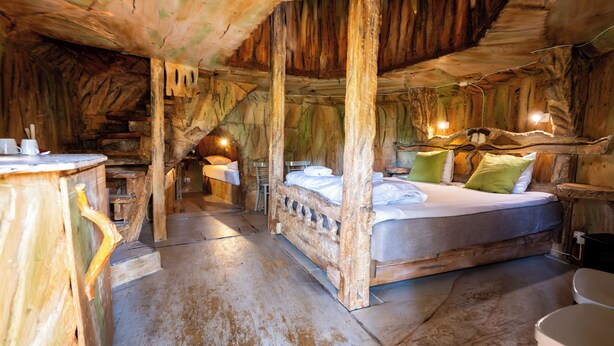 A rustic wooden room with a bed, a small table, and a chair. - Norrqvarn Hotel & Resort by Vänerport (Lyrestad)