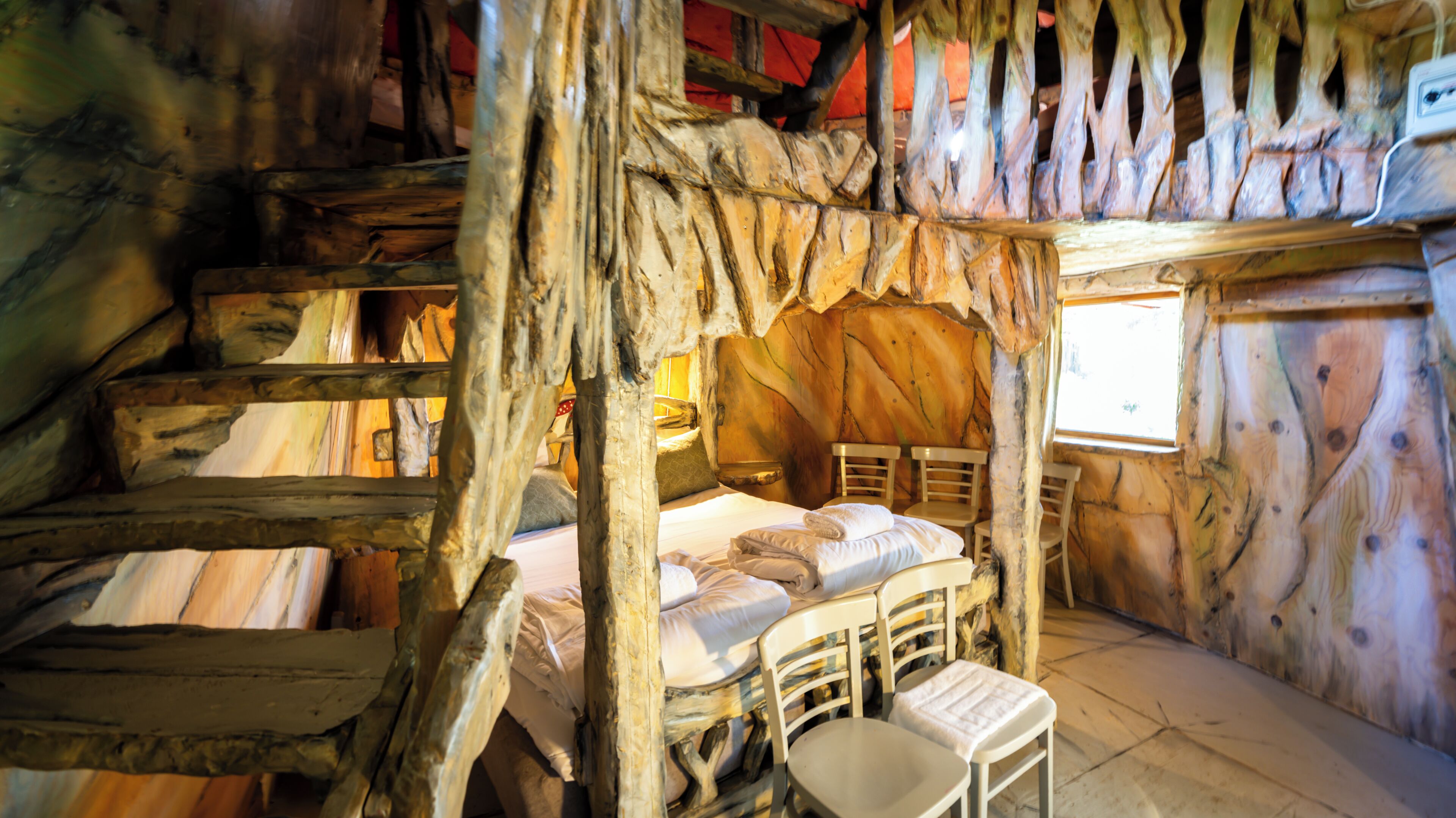 A rustic cabin with a bunk bed, a small table, and a window.