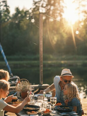 A dining table with food and drinks, surrounded by people. - Norrqvarn Hotel & Resort by Vänerport (Lyrestad)