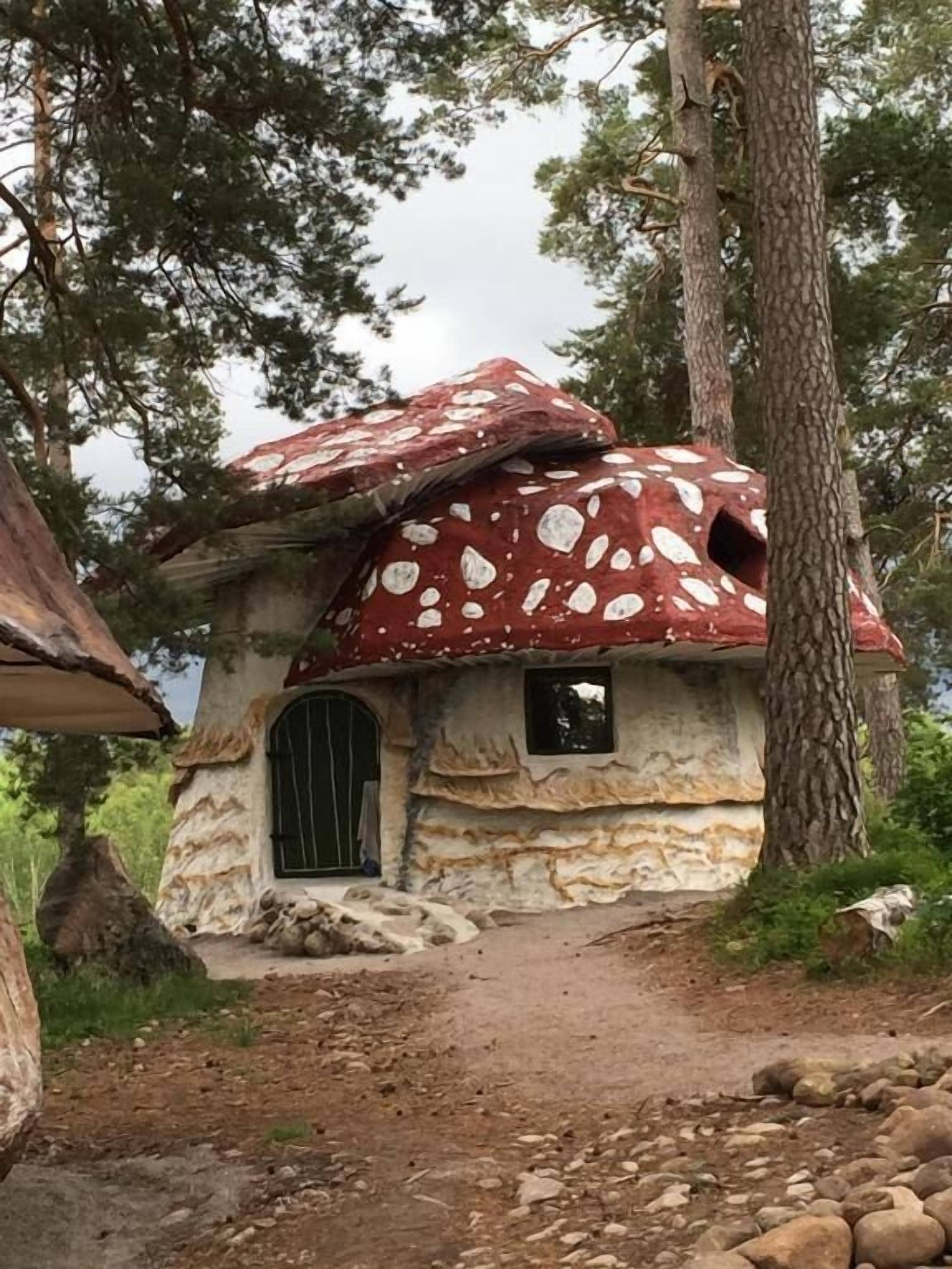 A mushroom-shaped house with a stone exterior, a small window, and a door.
