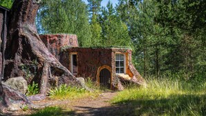 A rustic cabin nestled in a forest, with a dirt path leading to it. - Norrqvarn Hotel & Resort by Vänerport (Lyrestad)