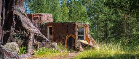A rustic cabin nestled in a forest, with a dirt path leading to it.