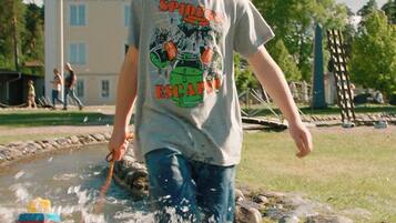 Un niño juega en una fuente de agua, con un edificio al fondo.