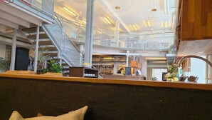 A spacious atrium with a staircase, seating area, and a bar. - Norrqvarn Hotel & Resort by Vänerport (Lyrestad)