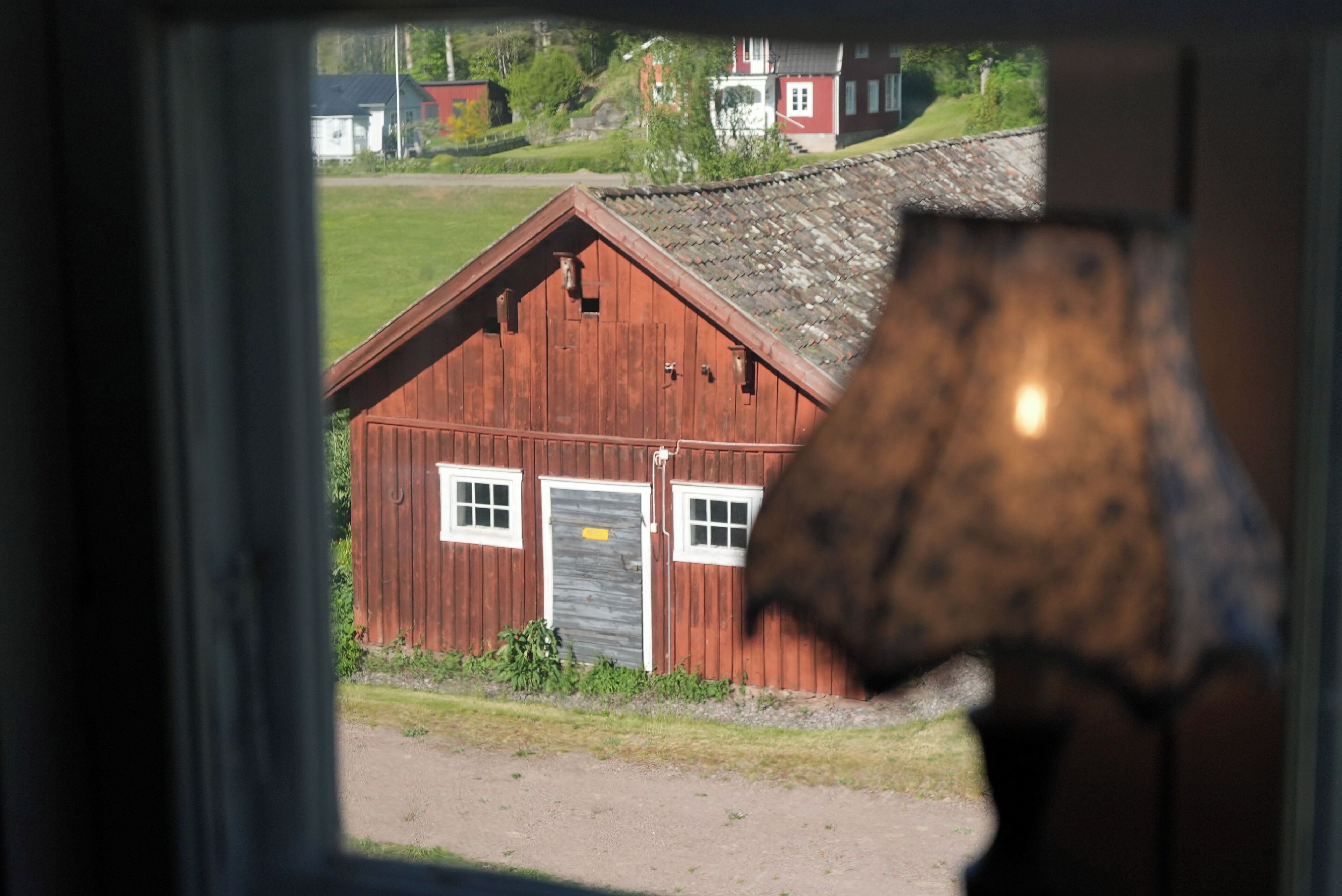 A red wooden building with a sloped roof, a door, and windows.