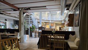 An interior with wooden tables and chairs, a staircase, and a view of the dining area. - Norrqvarn Hotel & Resort by Vänerport (Lyrestad)