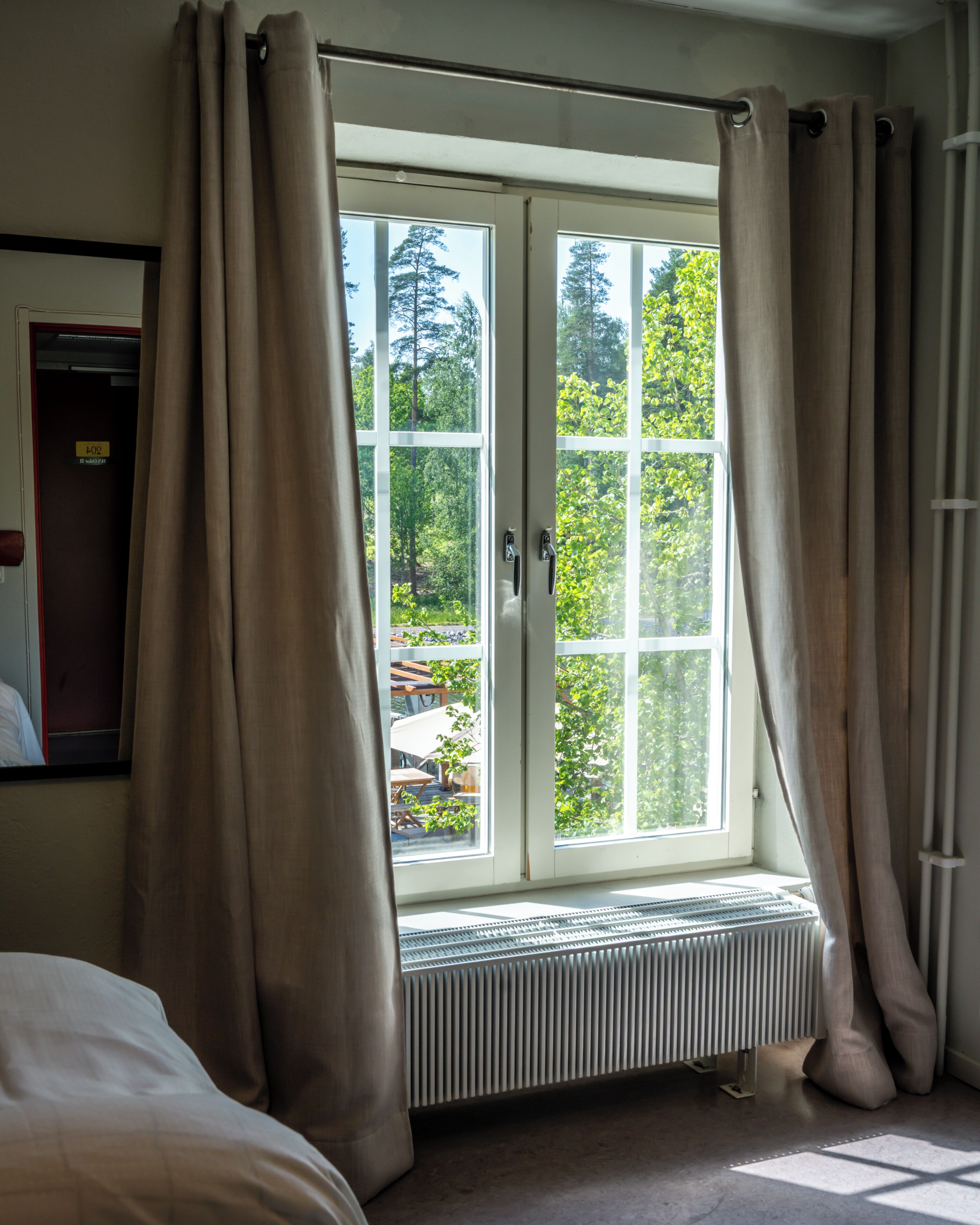 A room with a large window, a radiator, and curtains.