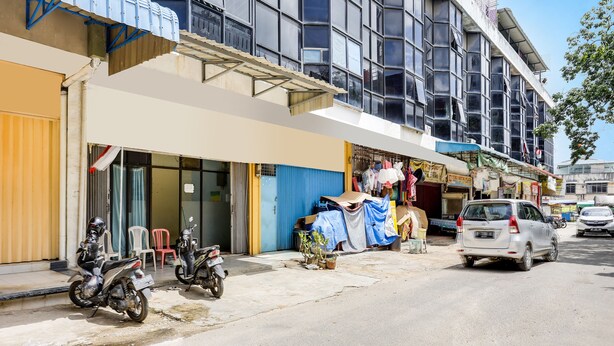 A street view with a building featuring multiple shops on the ground floor, a parked motorcycle, and a car on the road. - Hotel O Ringin Pitu 1 Syariah (Batam)