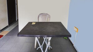 A small, dark-colored table with a single chair, a book on the table, and a small plant on the floor. - Hotel O Ringin Pitu 1 Syariah (Batam)
