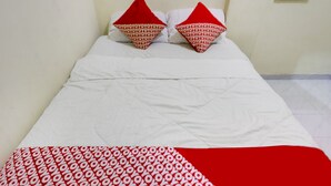 A bed with a white sheet and two red pillows with a repeating pattern. - Hotel O Ringin Pitu 1 Syariah (Batam)
