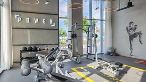 A gym with weightlifting equipment, a bench, and a wall with the word "POWER". - Aya - Outstanding 1BR Apartment With Amazing Creek Views (Dubai)