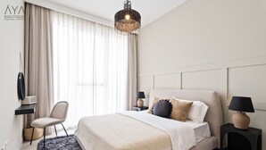 A modern bedroom with a large bed, a chair, a desk, and a hanging light fixture. - Aya - Outstanding 1BR Apartment With Amazing Creek Views (Dubai)