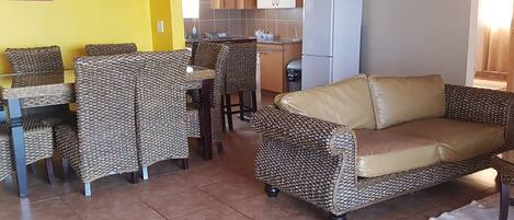 A living room with a yellow wall, a sofa, and wicker chairs.