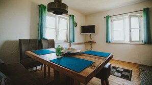 A dining area with a wooden table, blue placemats, a bottle, and a plate. - Apartment Hochalm at 1705m, at the foot of the Alpspitze (no access by car)  (Garmisch-Partenkirchen)