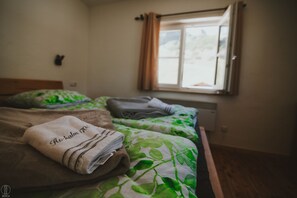 A bedroom with two beds, a window with curtains, and a wall-mounted light switch. - Apartment Hochalm at 1705m, at the foot of the Alpspitze (no access by car)  (Garmisch-Partenkirchen)