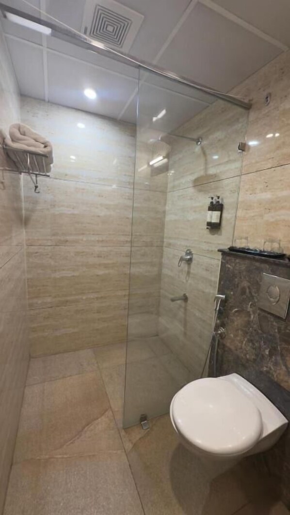 A modern bathroom with a glass-enclosed shower, a white toilet, and a marble wall.