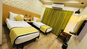 A hotel room with two beds, a desk, a chair, an air conditioning unit, and a TV. - Regenta Inn Bannerghatta Bangalore (Bengaluru)