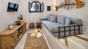 A cozy living room with a sofa, a wooden cabinet, a television, and a wall-mounted fish skeleton decoration. - Mystagoge Retreat with subterranean pool/jacuzzi (Vothonas)